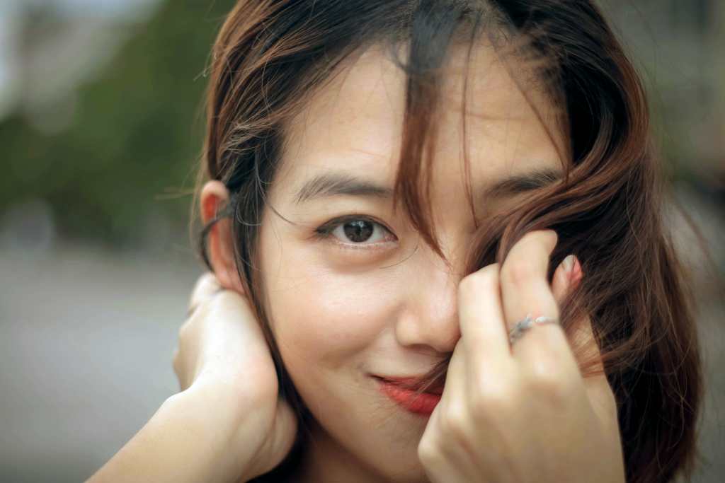 Woman holding hair in front of her face. She is showing off the effects of a home self treatment combined with facial plastic surgery on Oahu