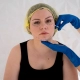 Hawaii plastic surgeon wearing blue gloves evaluates a patient's jawline prior to facial fat grafting.
