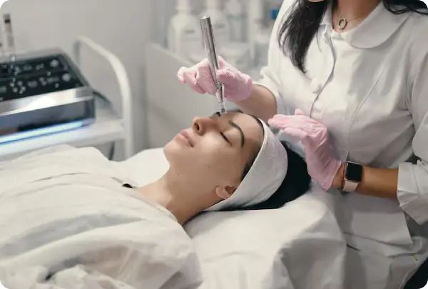 A Hawaii Facial Plastic Surgery specialist in a white coat and pink gloves using a SkinPen microneedling device on a patient’s forehead to stimulate collagen for advanced skin revitalization with PRP.